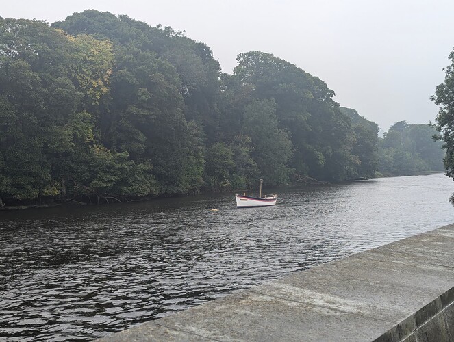 High quality image of a boat going down a river, you can see parts of a wall