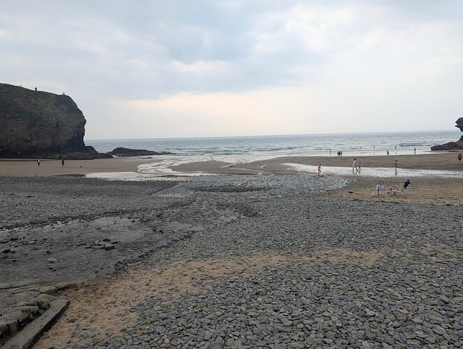 High quality image of a stream running down a beach with rocks scattered around