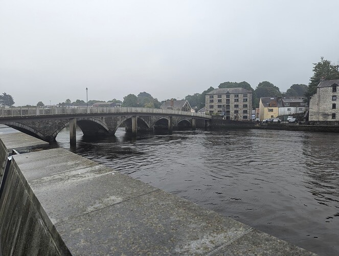 High quality image of a bridge going over a river with some multi-storey buildings in sight