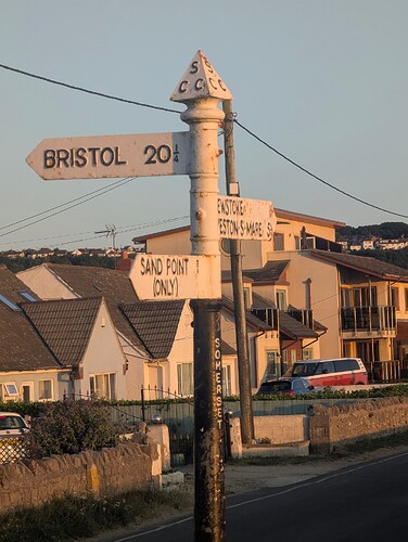 High quality image of a signpost with various houses in the background pinpointing Bristol, Sand Point and Weston-super-mare