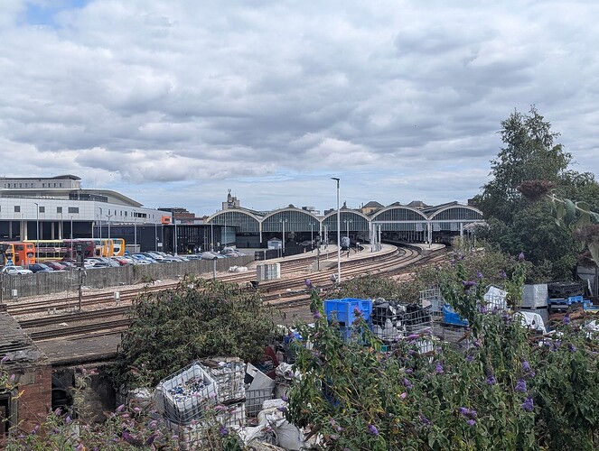 High quality image of train tracks leading into a train station. You can see what looks to be rubbish to the right.