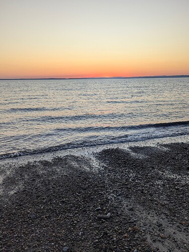 High quality image of the water coming towards the beach with a view of the sunset