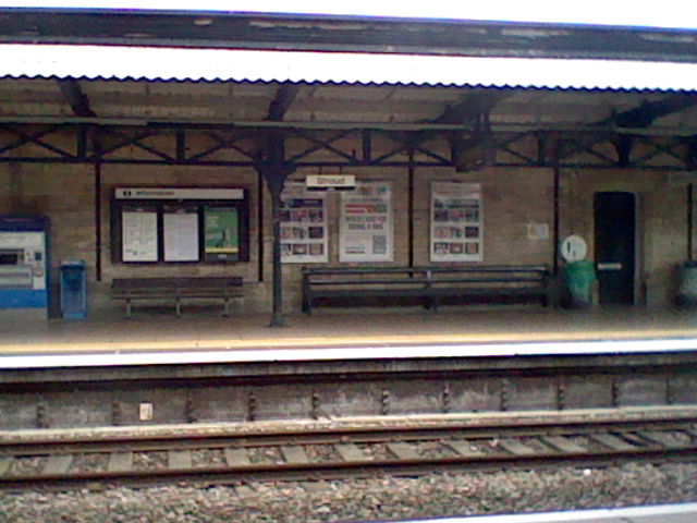 Train tracks and various signs on a brick wall