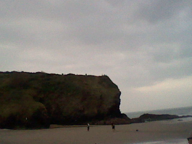 Low quality image of a cliff overlooking a beach, some people can be seen