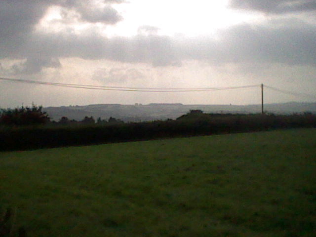 Low quality landscape image of electricity pylons, a hedge and hills