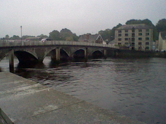 Low quality image of a bridge going over a river with a multi-storeybbuilding on the other side