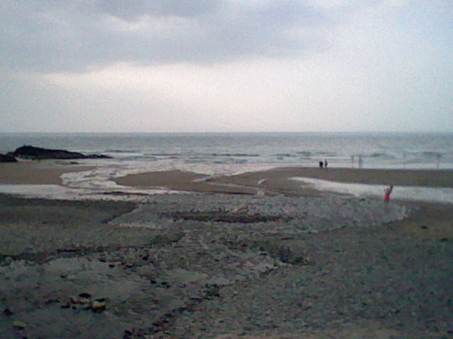 Low quality image of a stream running down a beach with rocks scattered around