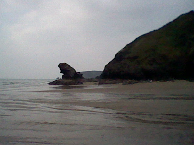 Low quality image of a group of rocks on a beach along with a cliff